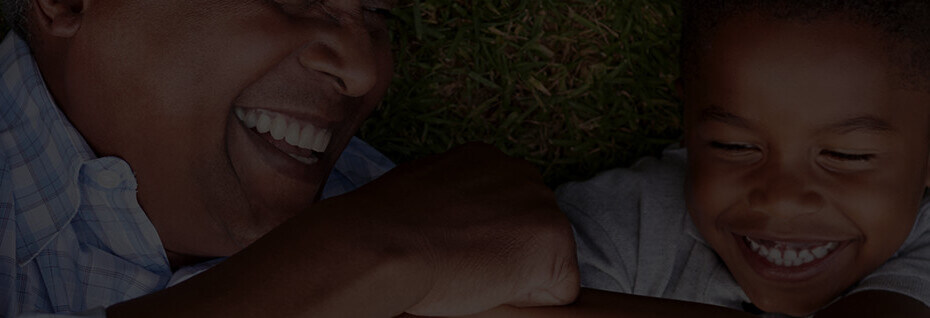 Father and son laying on the grass smiling