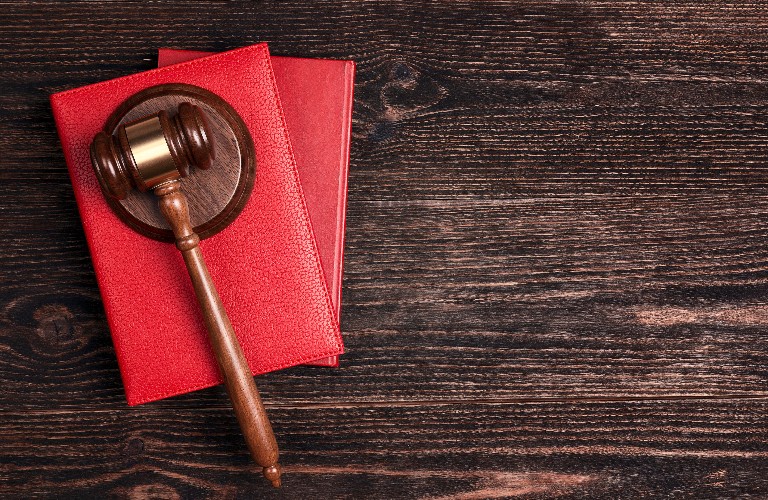 Wooden judges gavel lying on legal books on wooden table