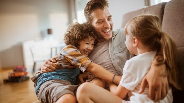 Happy father hugging two kids at home