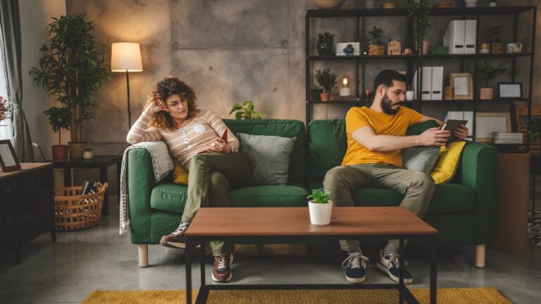 man and a woman are sitting on different sides of the sofa