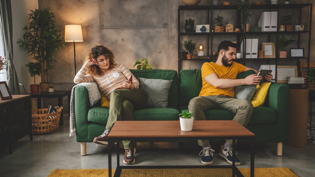 man and a woman are sitting on different sides of the sofa